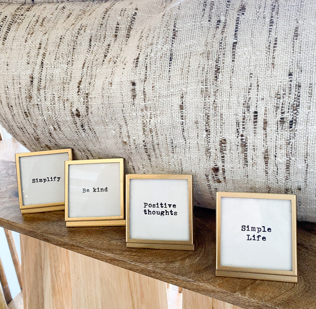 small gold frames lined up on a shelf with sayings written on them