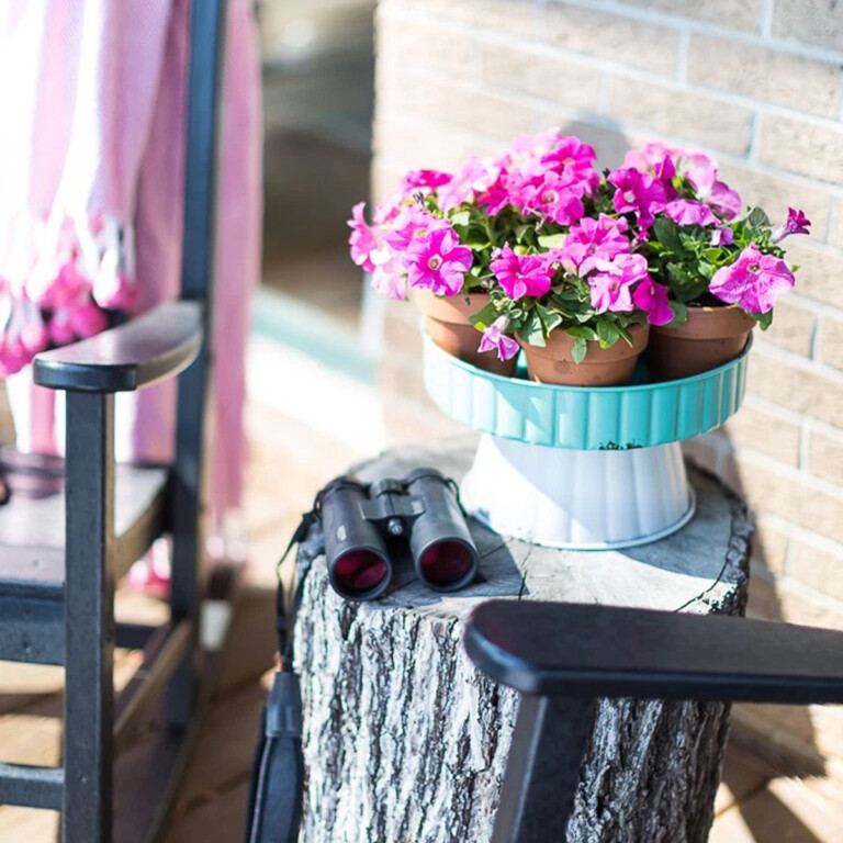 a tree stump made into an outdoor table with pink petunias on it.