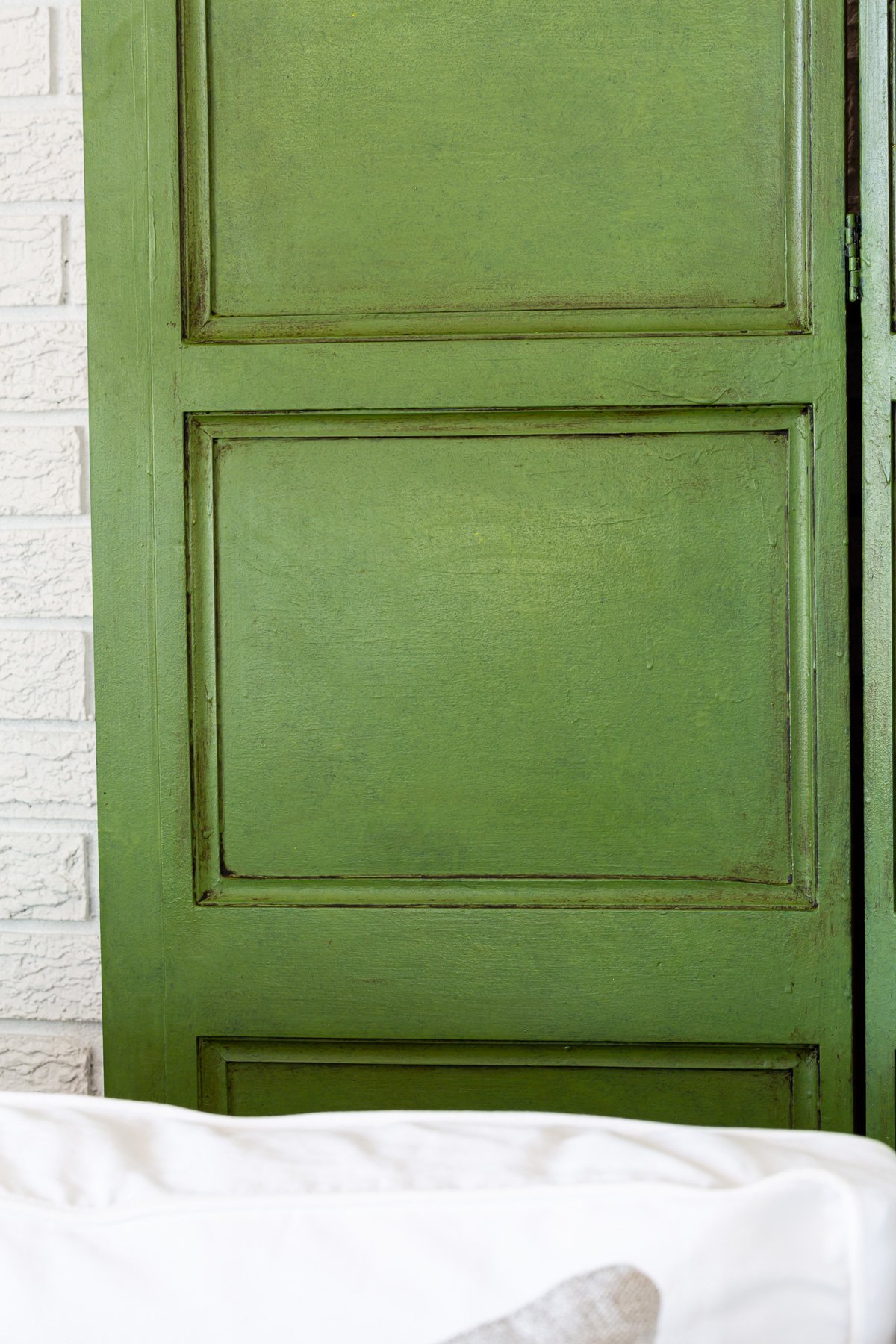 Close up photo of a green paint and glazed wood screen.