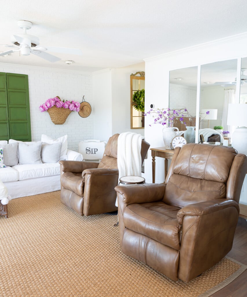 Rearranged living room furniture for summer. 2 identical recliners and white sofa. Pink and green accents in room.