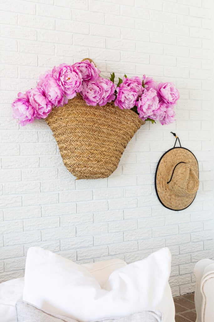 basket tote filled with pink peonies hanging on living room wall.