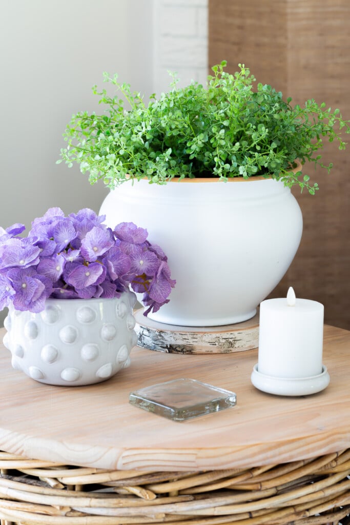 White spray painted planter on round wicker table in living room.
