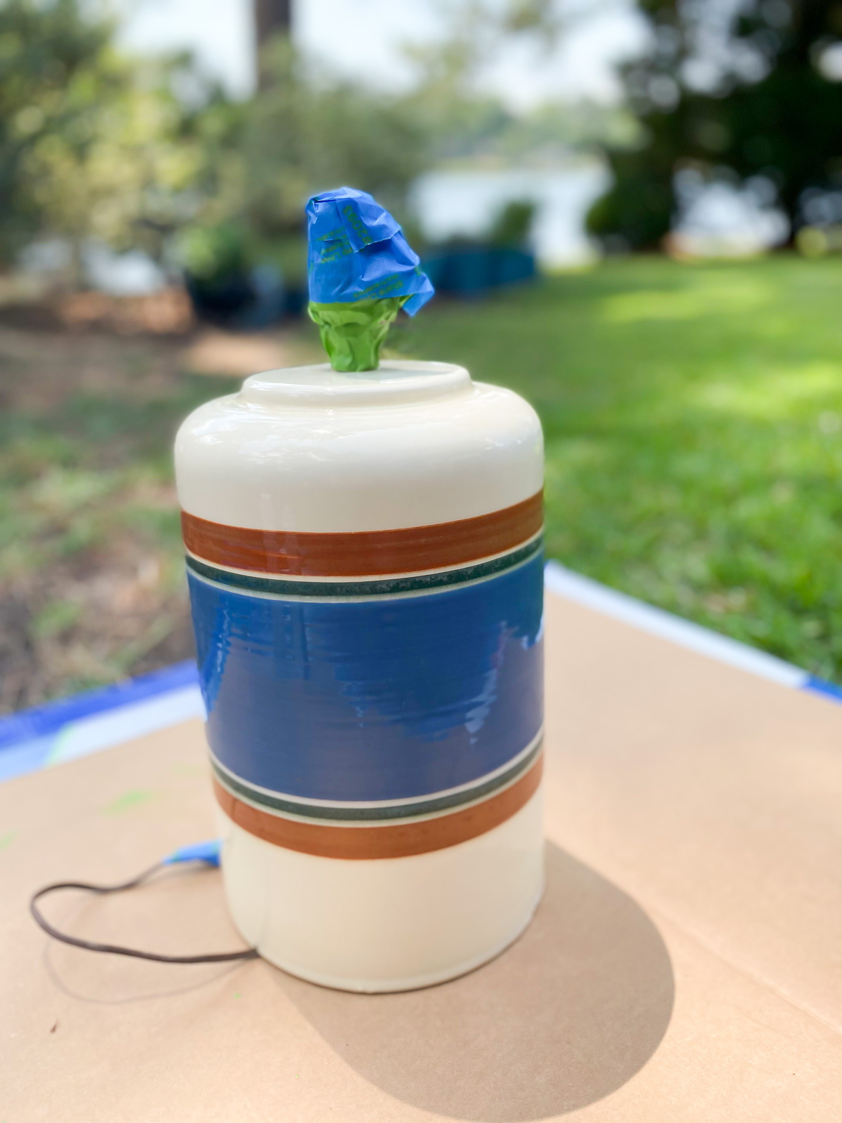 Thrift store lamp set up outside on cardboard ready to be spray painted.