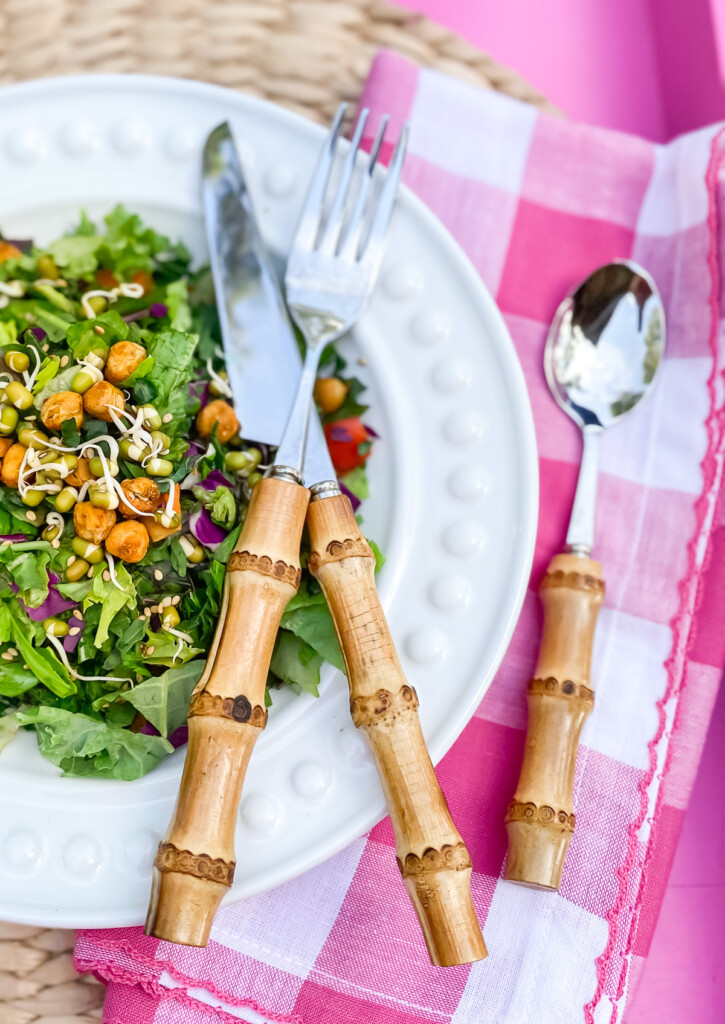 white dinner plate with salad on it. On a pink tray to dine alfresco.