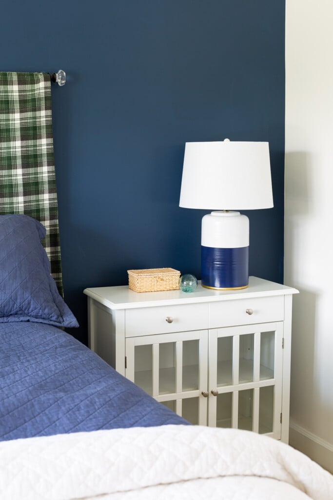 Blue and white bedroom with painted table lamp on nightstand.