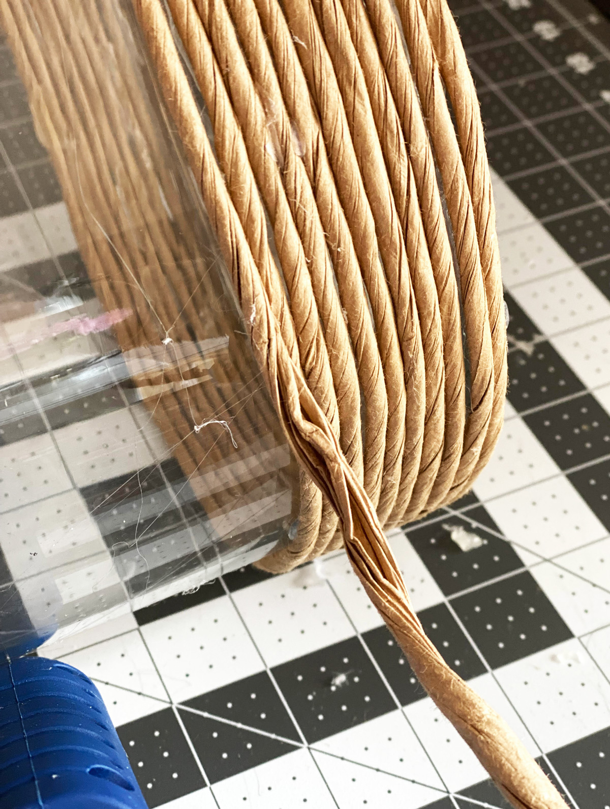 paper cord being wrapping and glued onto a glass vase on worktable