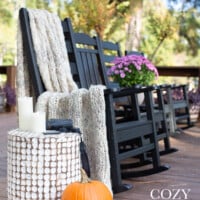 outdoor rockers lined up on a deck decorated for fall