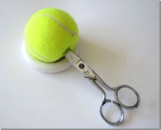 tennis ball being cut with scissors