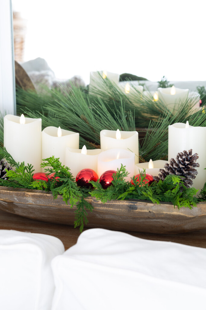 white battery operated candles and greenery in dough bowl on console table