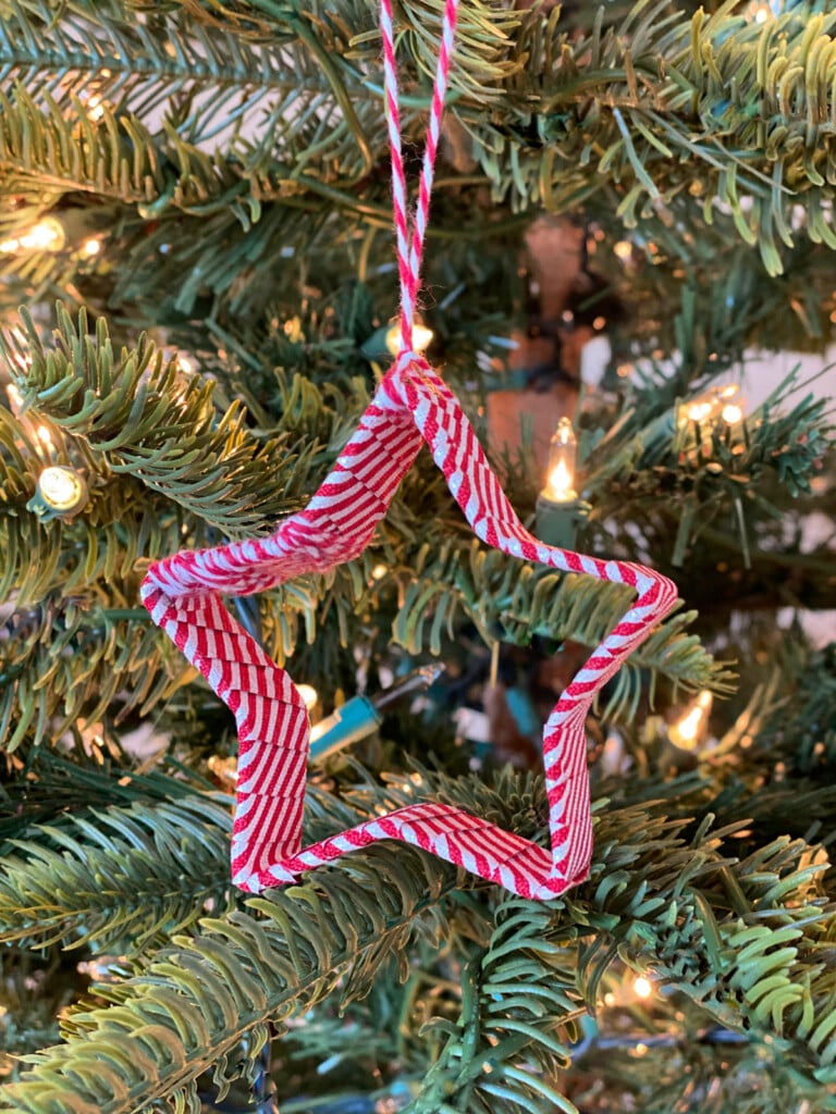 red and white striped ribbon covering a star cookie cutter to make an Christmas tree ornament.