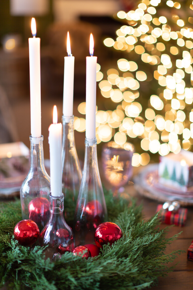 White candles in clear bottles become a budget Christmas dinner table centerpiece.