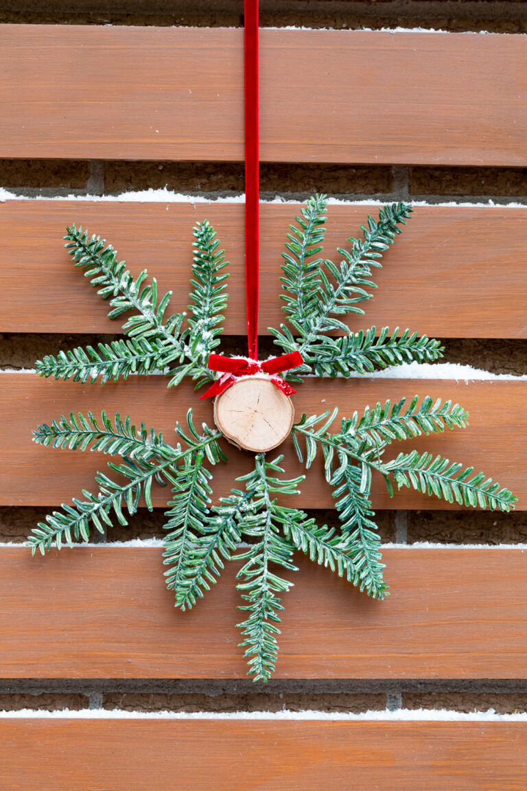 Tree trunk and pine branch Christmas wreath hung on red ribbon outside