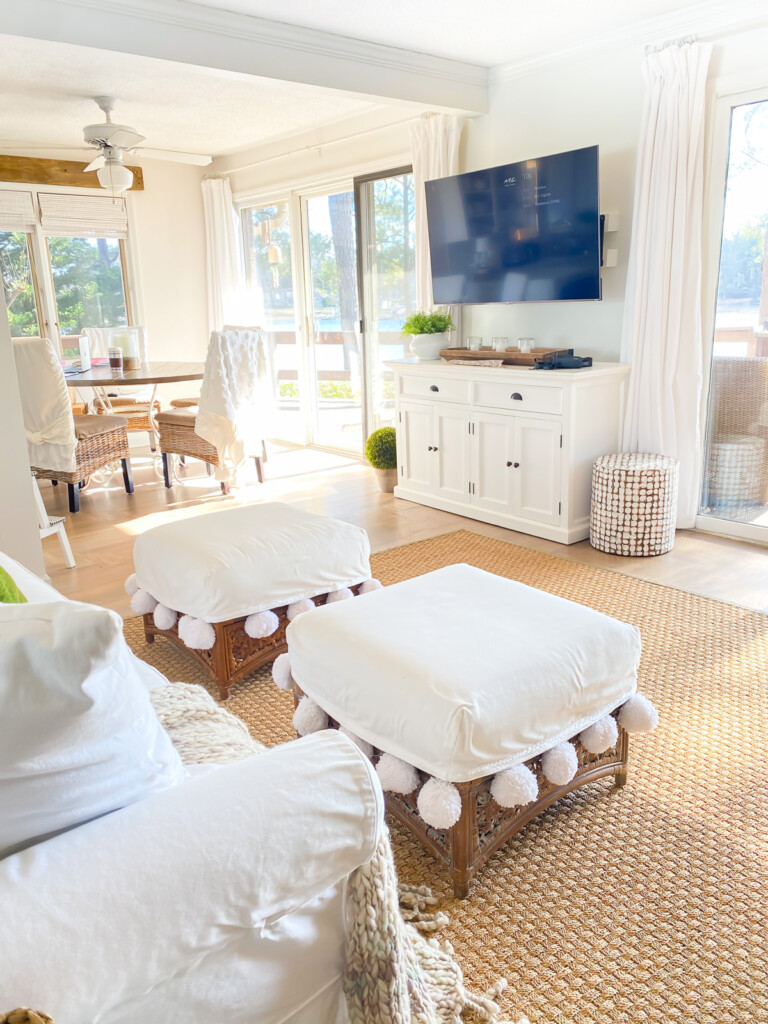 Two square pom pom trimmed ottomans in a living white and neutral living room.
