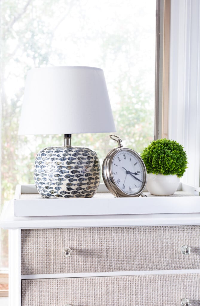 table lamp on night table with clock and greenery