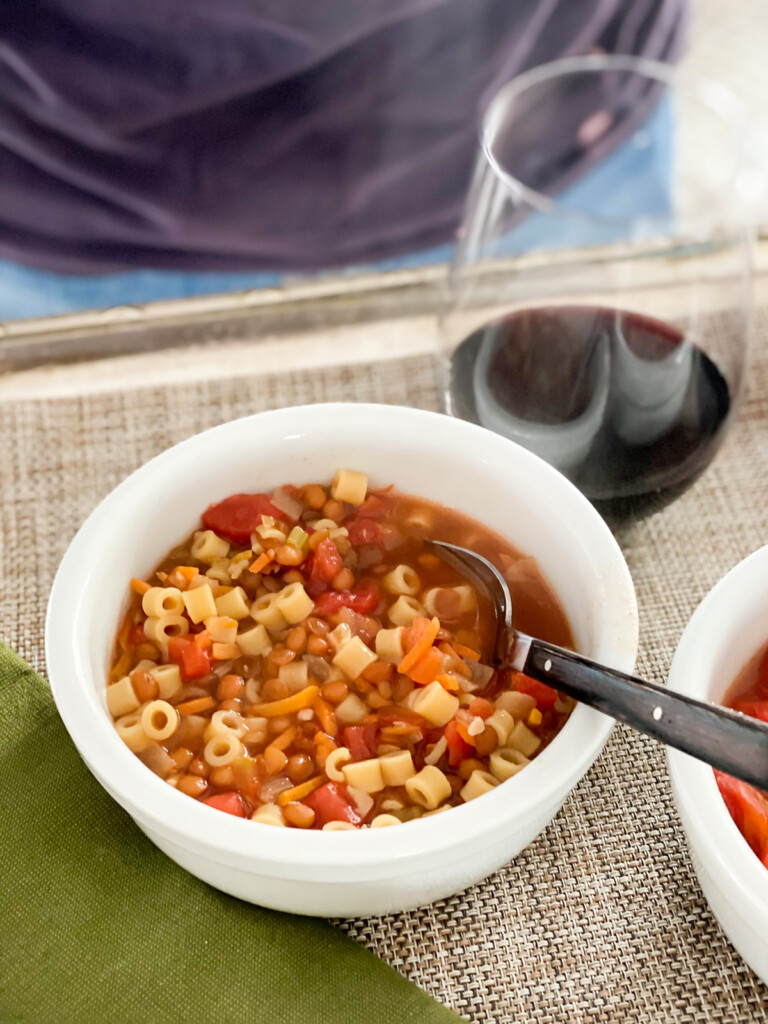 A bowl of Rustic Tomato Soup and a glass of red wine on a tray.
