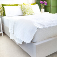Upholstered Platform bed in a bright and cheery white and green guest bedroom.