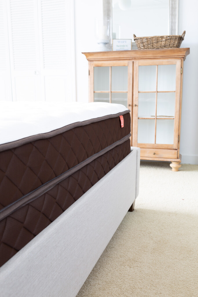 side view of a Christeli Charleston 14.5 mattress and base in an Eastman upholstered platform bed in a bedroom.