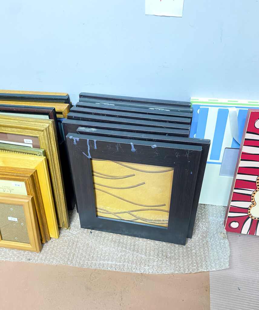 frames stacked against wall at a thrift shop