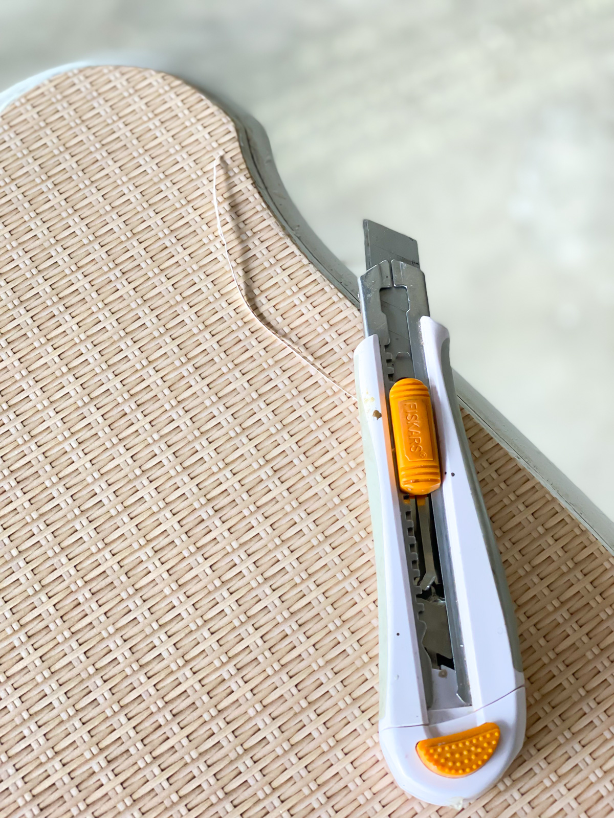 craft knife trimming the edge of wallpaper on furniture.