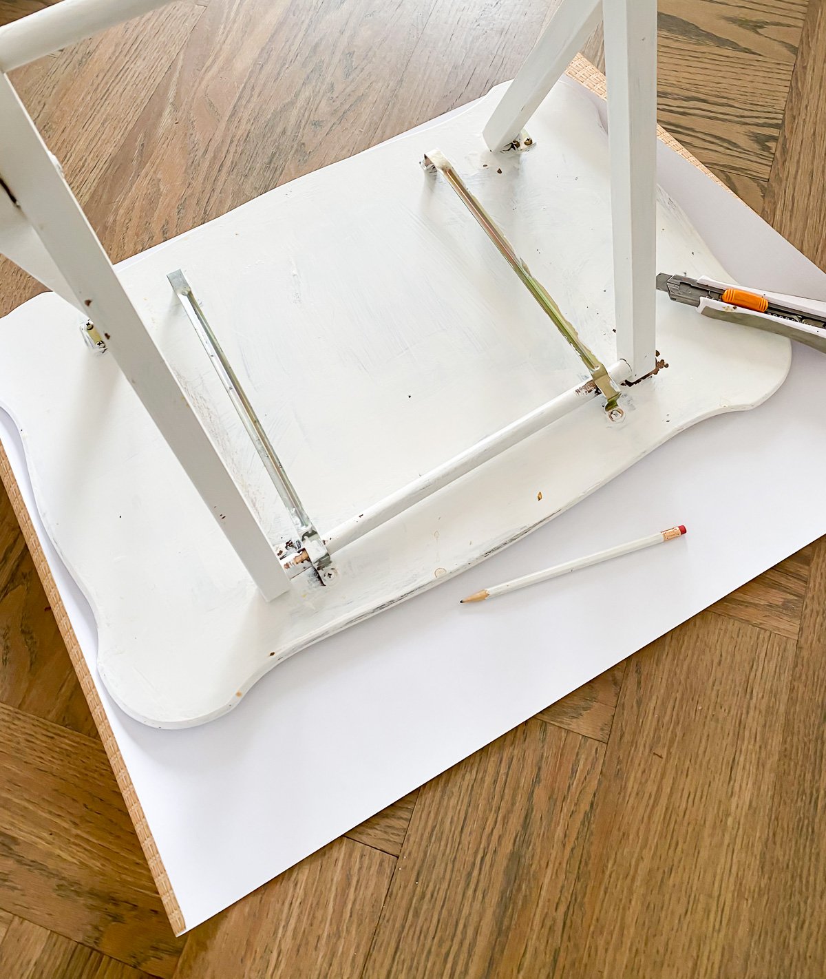 tray table placed upside down on wicker print paper so a tracing of the top can be made to perfectly fit the top shape.