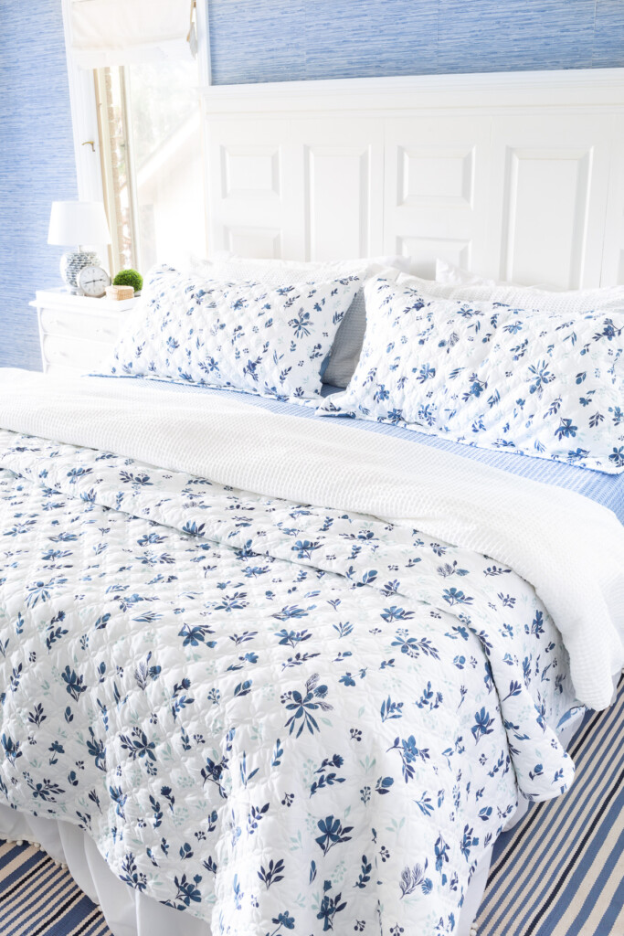 Reversible floral bedspread and pillow shams on a bed in the colors blue and white.