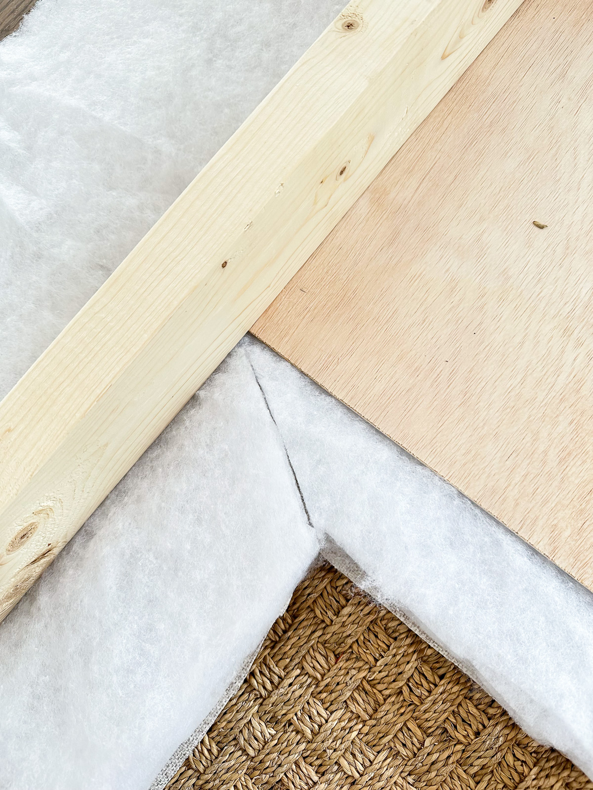 Wood frame of headboard being wrapped in batting and fabric.