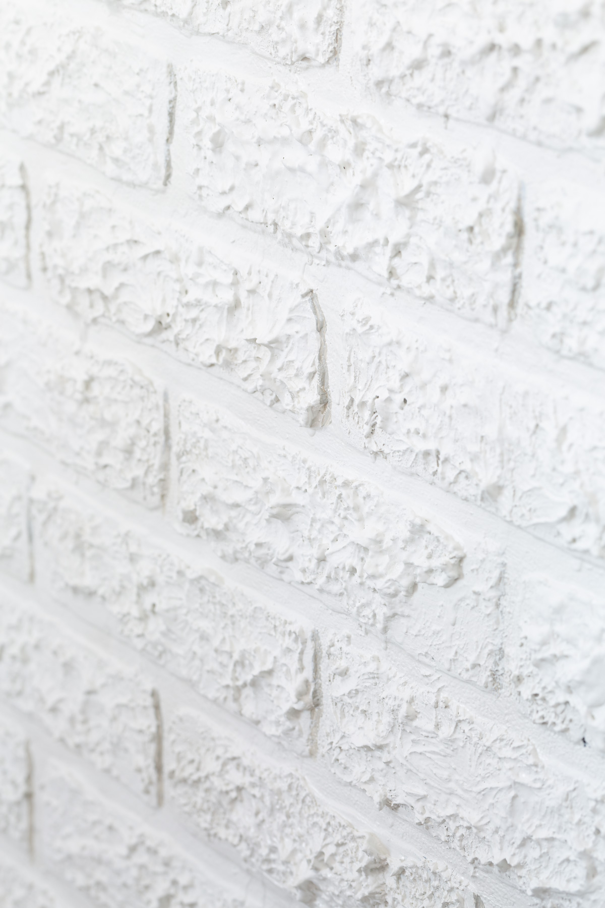 close up of faux brick paneling with spackle added to provide texture to match brick wall around it.
