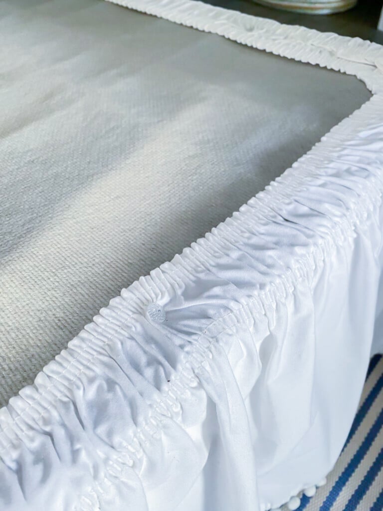 An elastic topped white bed skirt with twist pins to hold it in place.