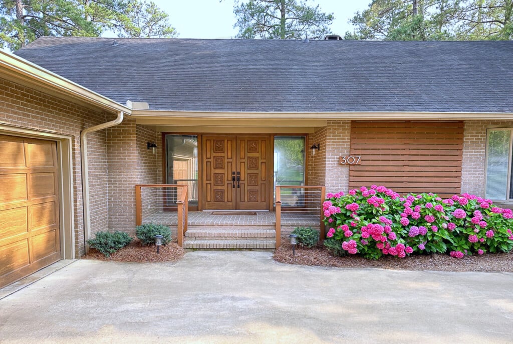 Completed DIY cable railing on a brick front porch of a home.