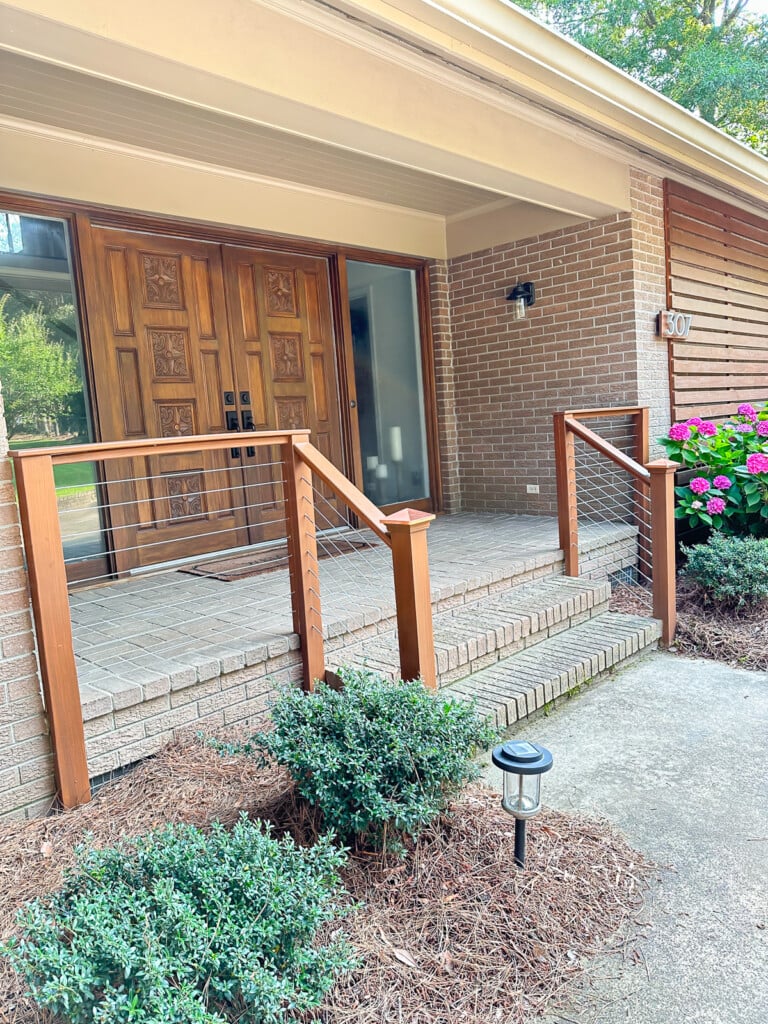 brick front porch railing being stained before cable railing sections added.
