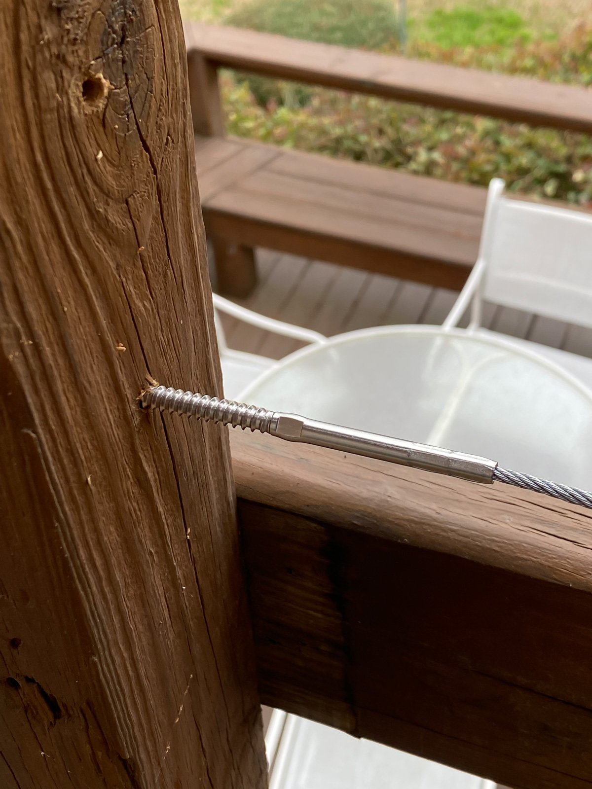 Deck Man cable railing screw with cable attached into wood deck post.