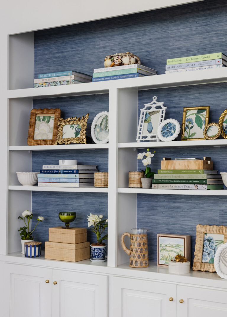 white shelving unit with blue grasscloth paper behind it