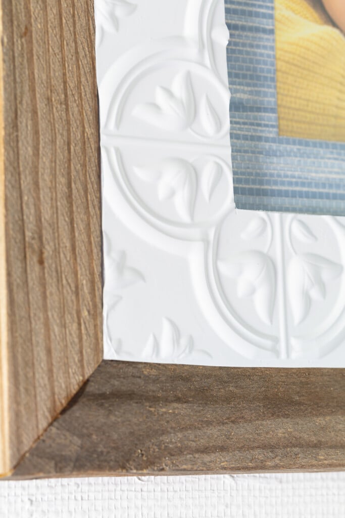 close up of thrifted frame with wood added and adhesive tile and wallpaper scraps.