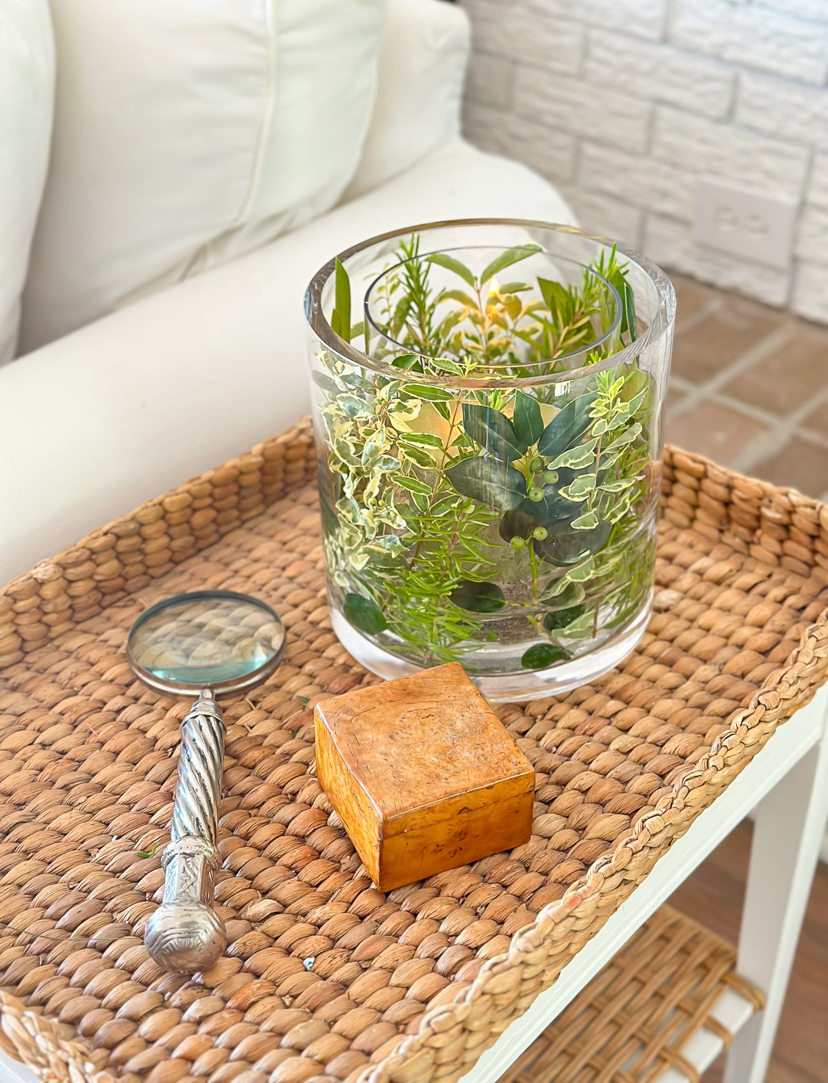 Summer table decor that uses two glass vases and herbs and shrub cuttings from a yard. Placed on a table makes a nice candle vase.
