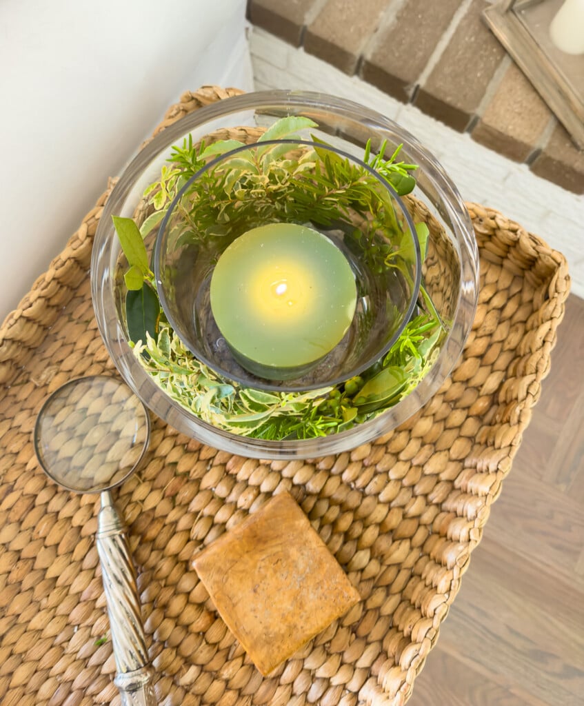 Looking down into a glass candle vase DIY that is on a wicker tray table.