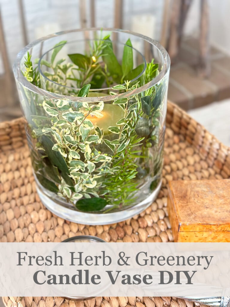 Fresh herb and greenery DIY candle vase on a wicker tray table in a living room.