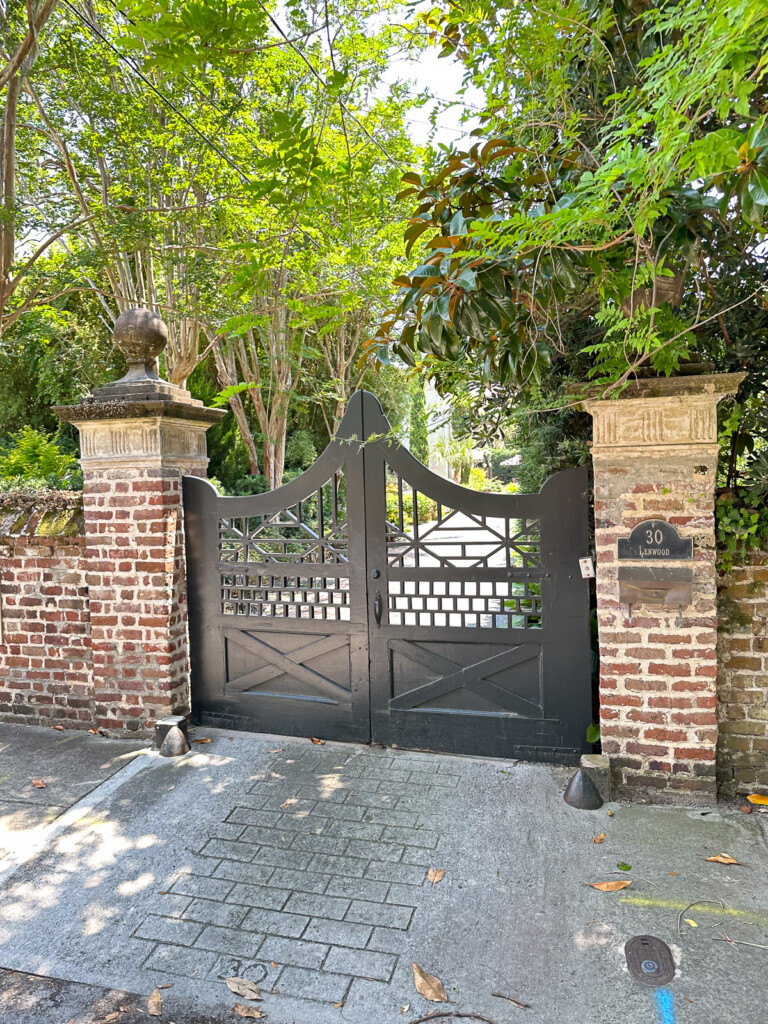 Ornate wood driveway door flanked by brick square columns.