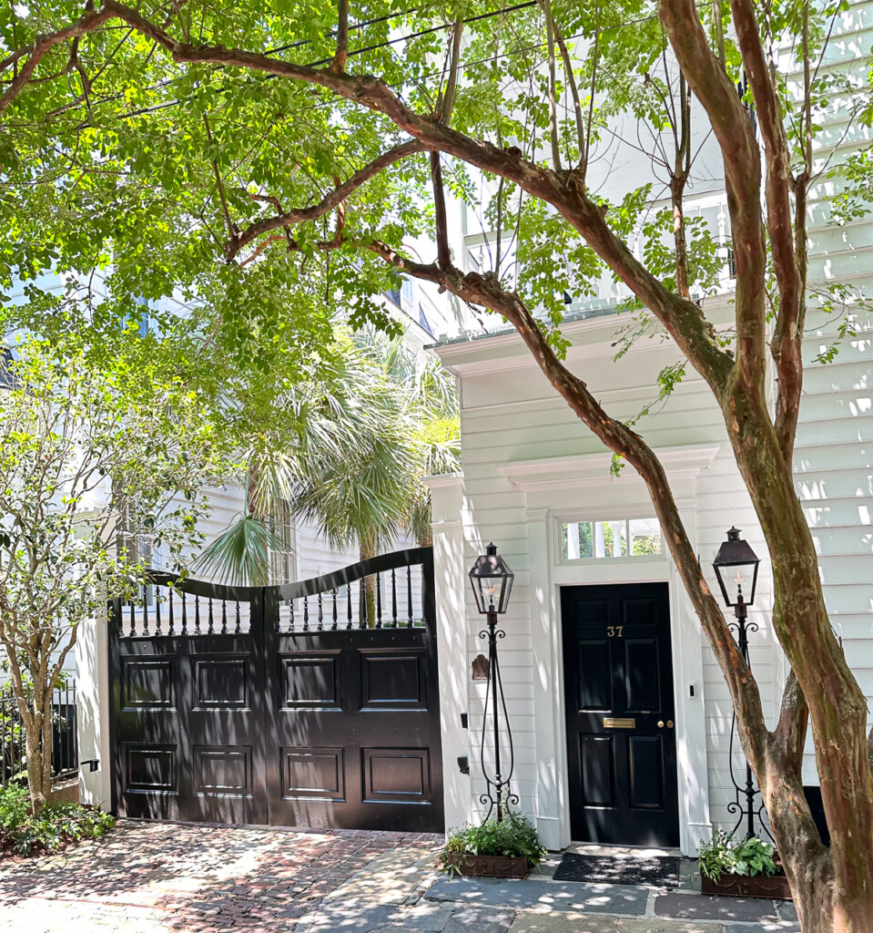 Ornate wood driveway doors painted black on a white house.