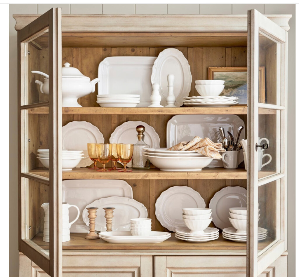 Pottery Barn light wood china cabinet with white dishes inside.
