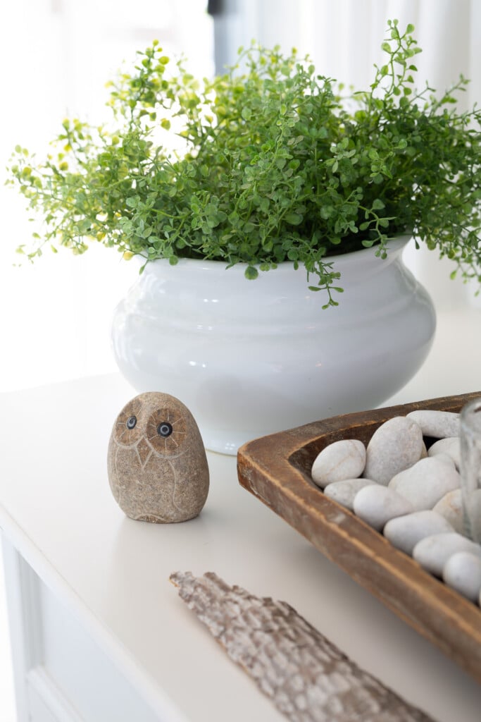 Stone owl and decorative accessories on a sideboard.