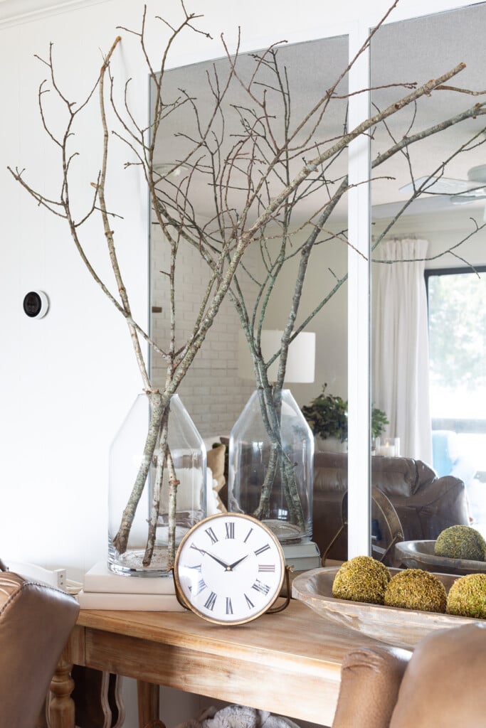 Tree branches in a large glass vase on a console table.
