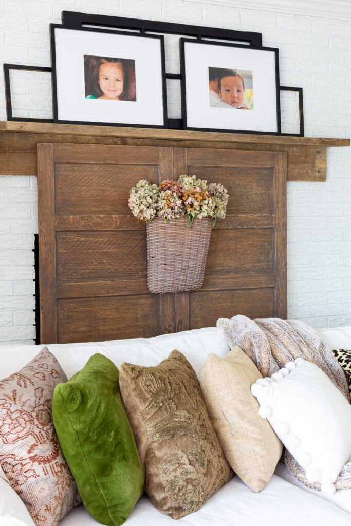 View of reclaimed wood fireplace mantel with black photos frames on top.