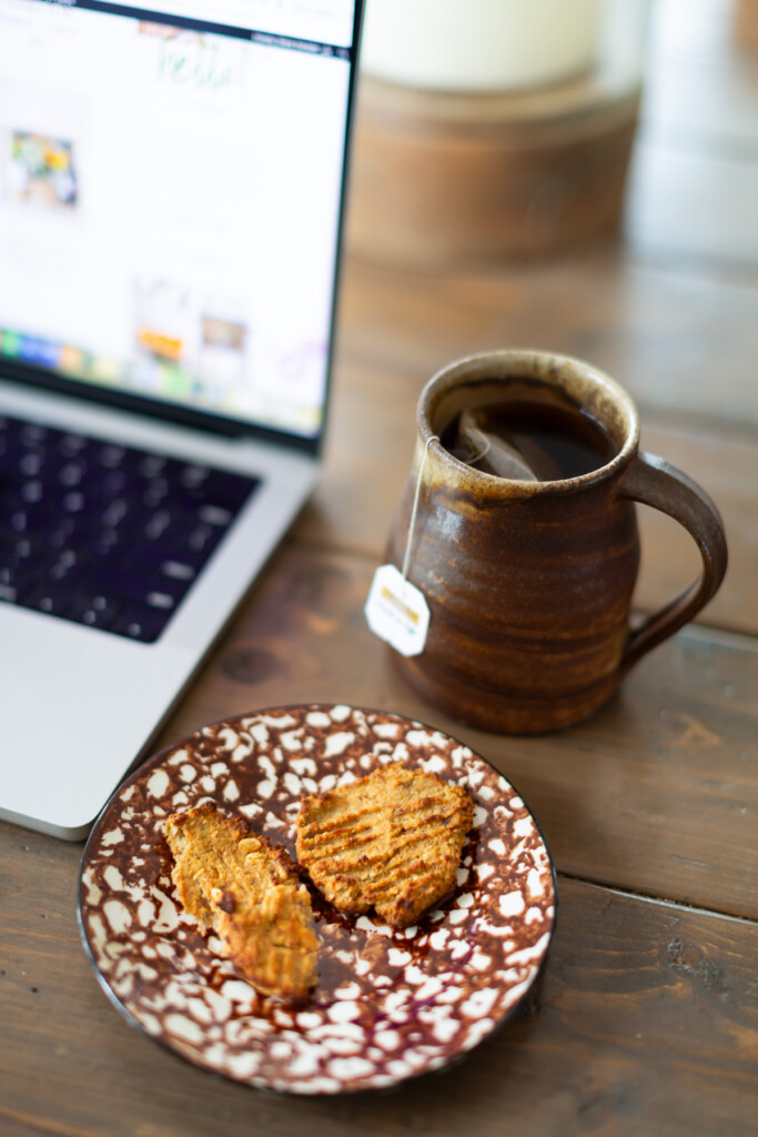 2 healthy homemade cookies on a plate with a cup of tea.