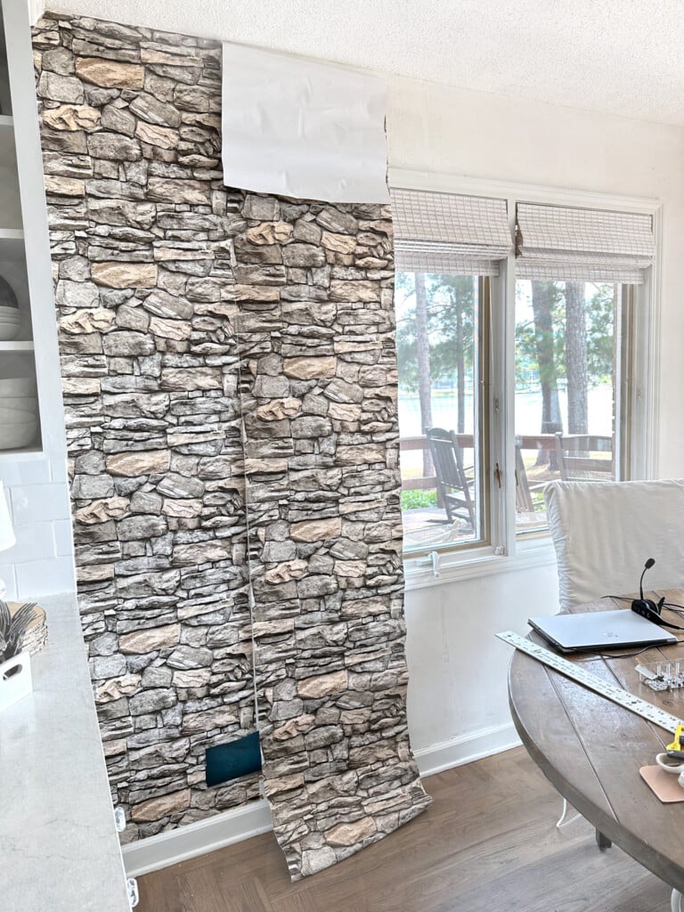 putting peel and stick wallpaper in a stacked stone pattern on a wall in a kitchen.