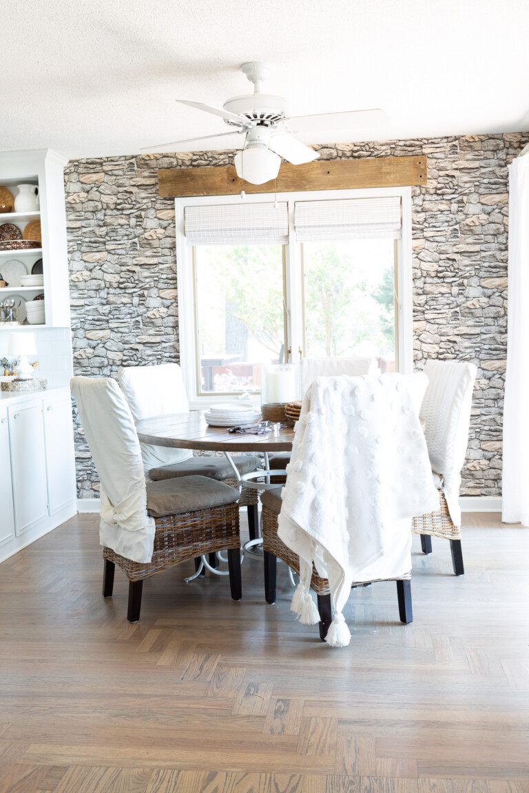Small kitchen dining area decorated in neutral colors with faux stone wallpaper on wall.