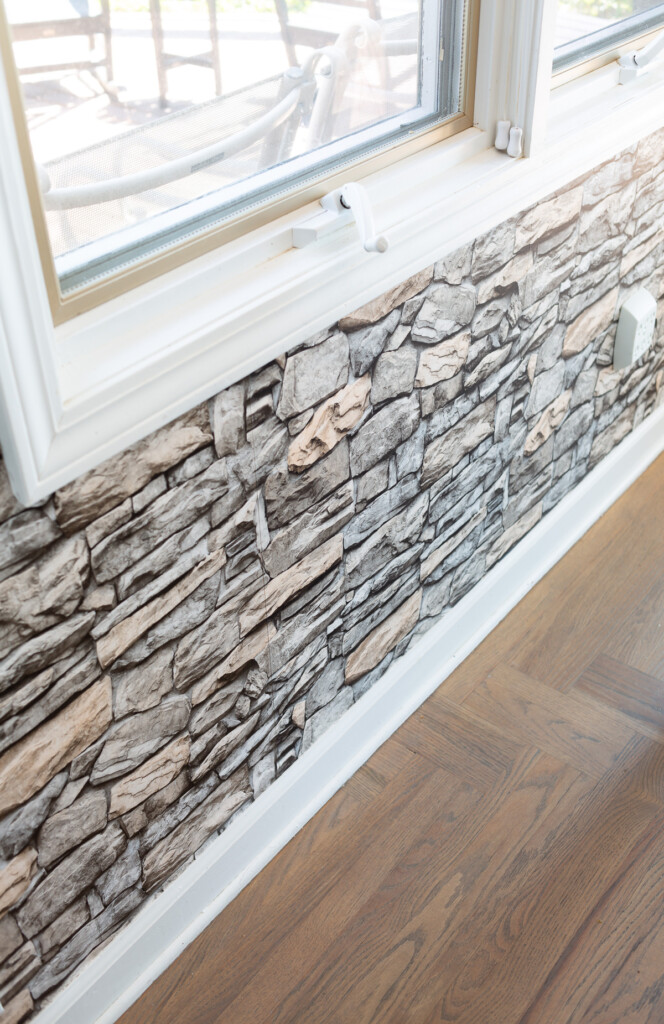 Faux stone wallpaper under a window on a wall in a kitchen.
