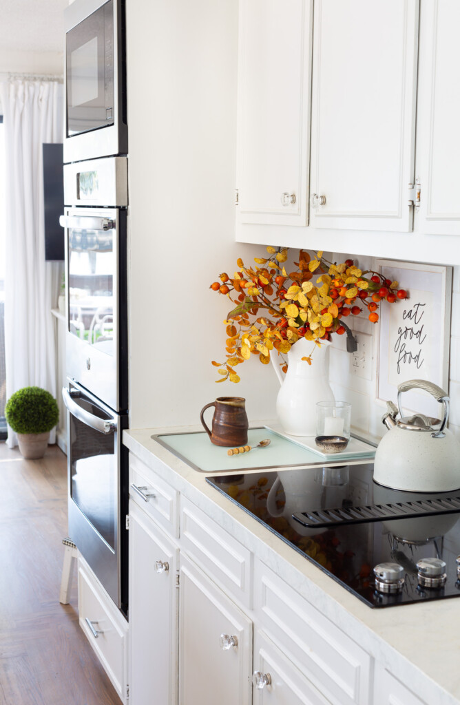 A few of one wall in a small white kitchen decorated for fall.
