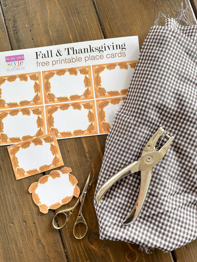 Fall & Thanksgiving free printable place cards, brown and white gingham fabric scissors and hole punch gathered on a table.