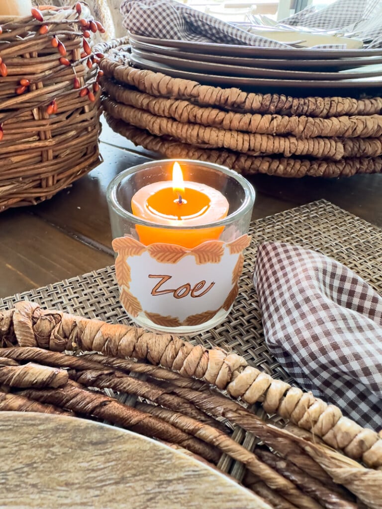 Burnt orange color votive candle in glass holder with free printable Thanksgiving place card hot glued to it.