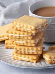 A stack of vegan custard creams with a cup of tea.